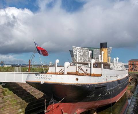 O SS Nomadic, último navio da White Star Line, ancorado em Belfast. O SS Nomadic desempenhou um papel crucial no transporte de passageiros do porto de Cherbourg para o Titanic, conectando os viajantes ao lendário navio.