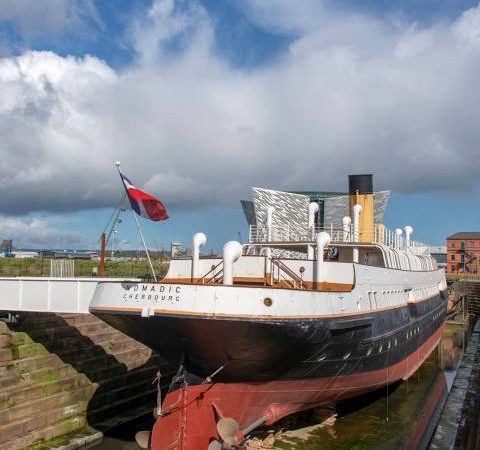 O SS Nomadic, último navio da White Star Line, ancorado em Belfast. O SS Nomadic desempenhou um papel crucial no transporte de passageiros do porto de Cherbourg para o Titanic, conectando os viajantes ao lendário navio.